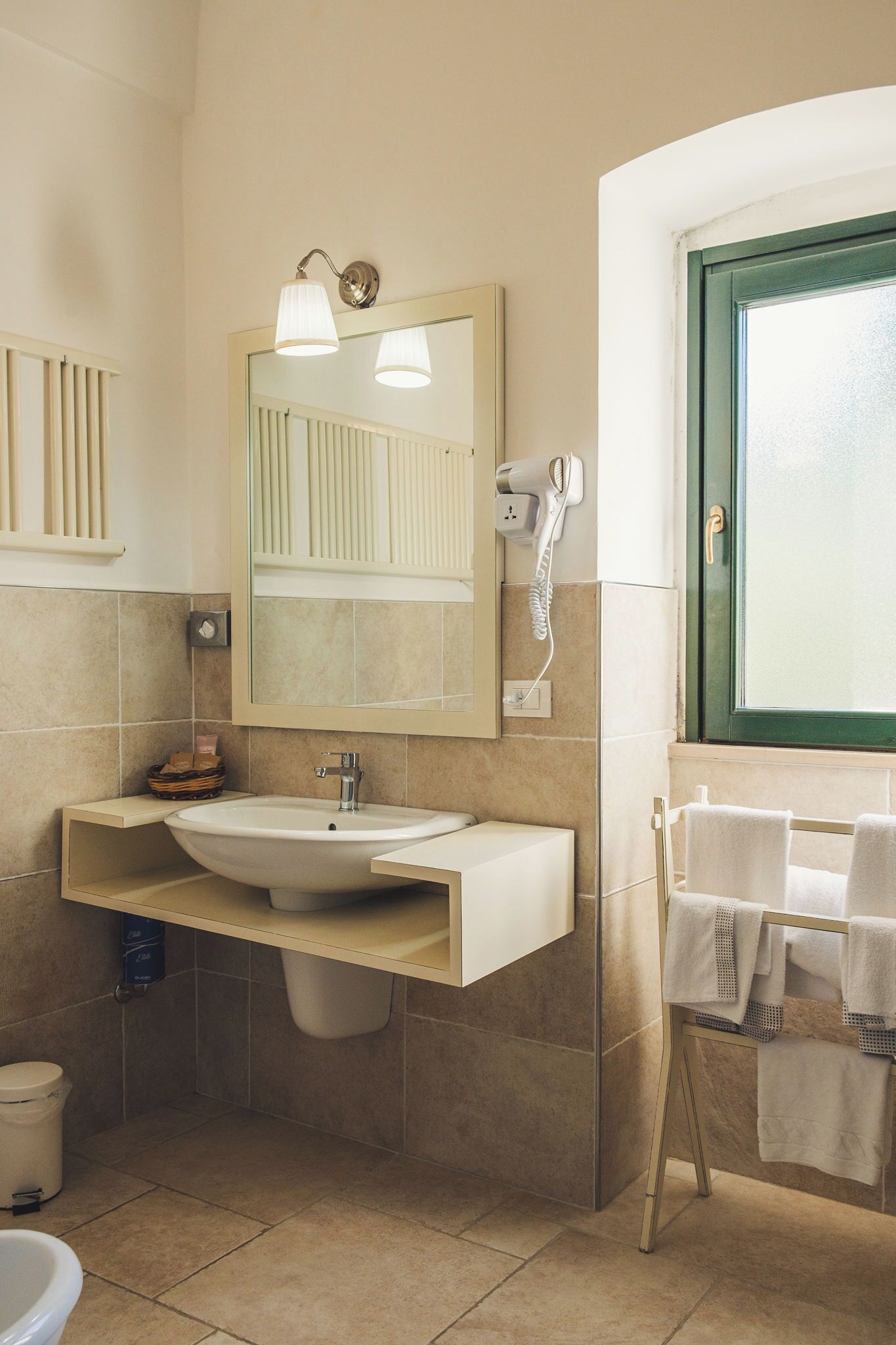 A bathroom with a sink, mirror, towel rack, and a window with a green frame.