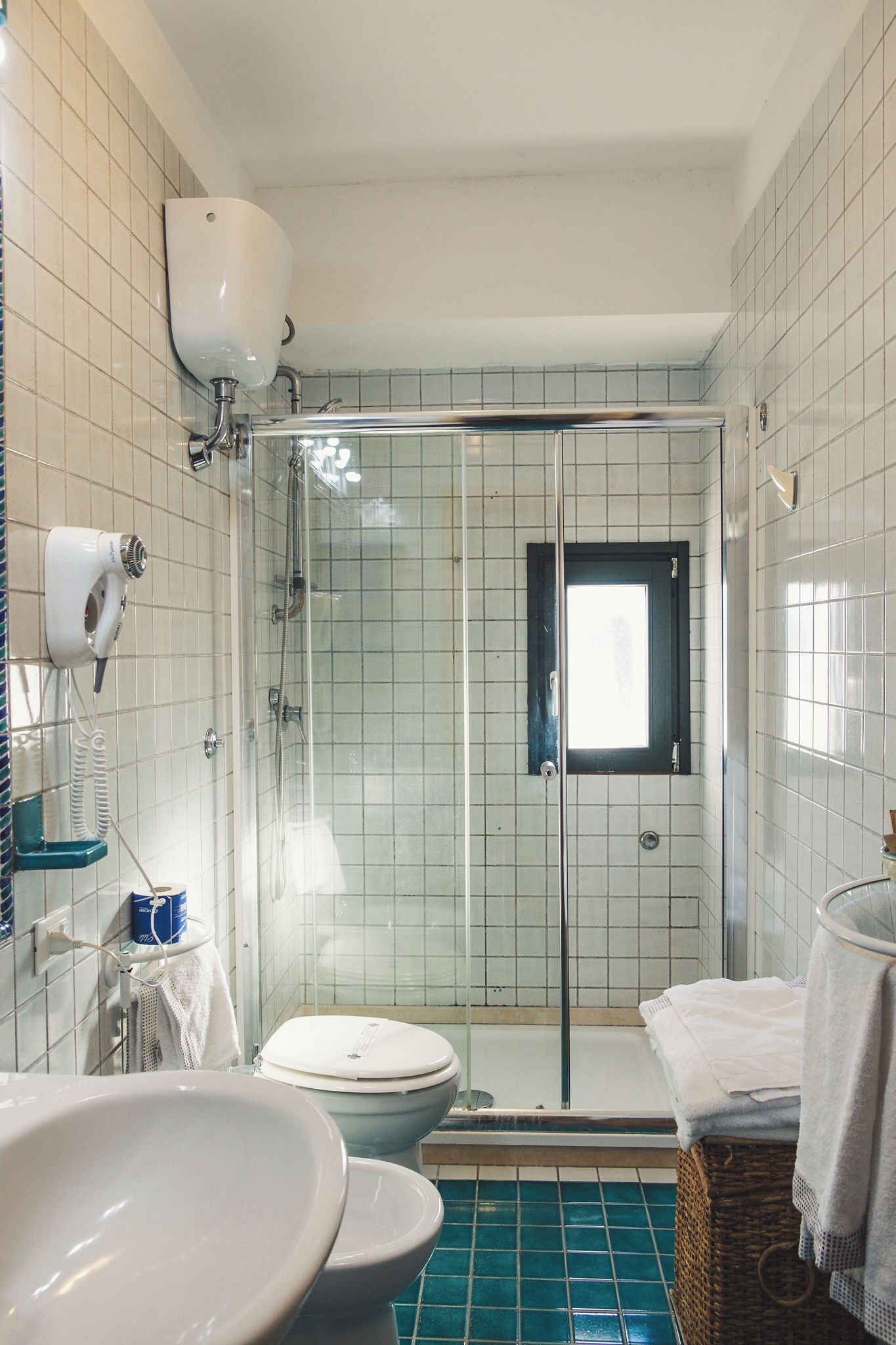A bathroom with a glass-enclosed shower, a toilet, and a sink.