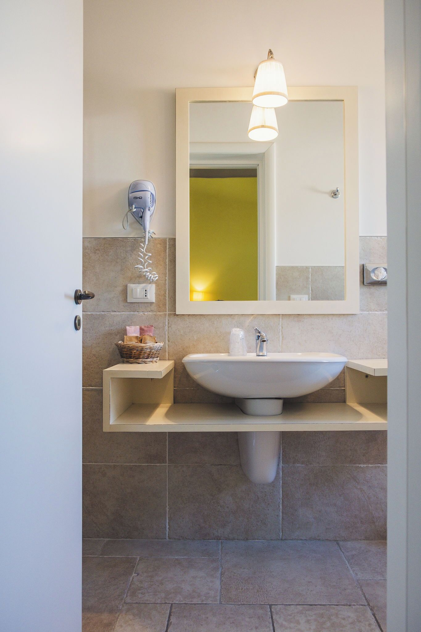 Een badkamer met een wit wastafel, een spiegel en een handdoekhouder.