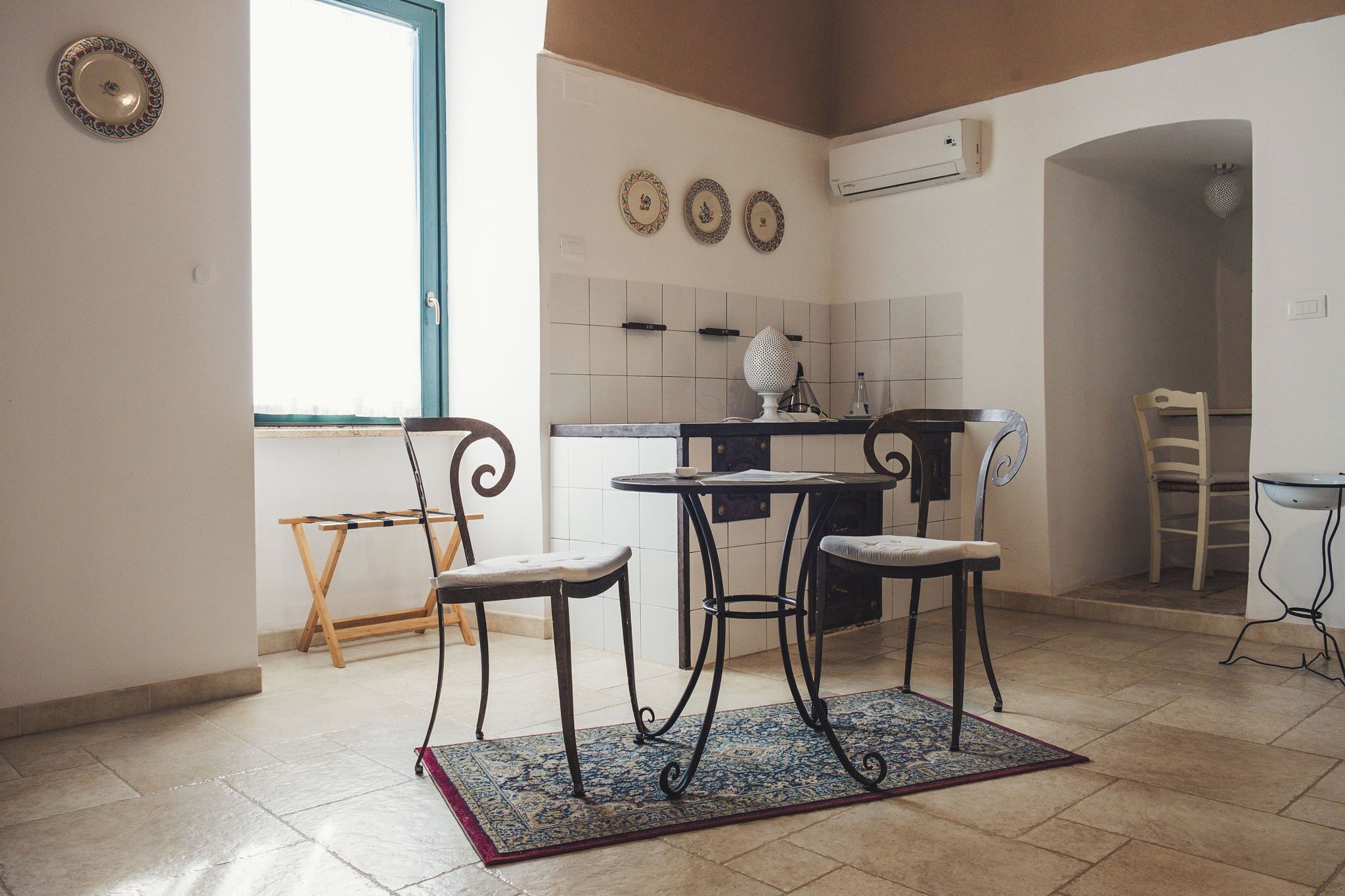 Cocina compacta con comedor, que incluye una pequeña mesa con dos sillas, una ventana y un salpicadero de azulejos.