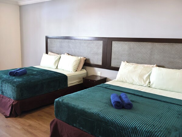Two twin beds with headboards, a wooden nightstand, and a wall-mounted power outlet.