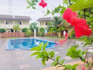 A swimming pool surrounded by greenery and a building in the background. - Shell Out Cenang Beach Resort (Langkawi)