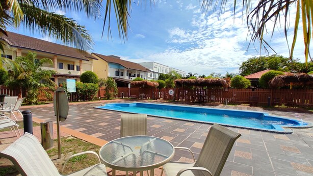 Un patio trasero con piscina, mobiliario exterior y una valla.