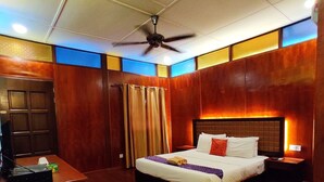 Una habitación de hotel con cama, mesita de noche y escritorio con computadora.