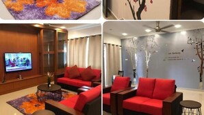 Un vestíbulo de hotel con sofás rojos, una mesa de centro redonda y una pantalla de televisión.