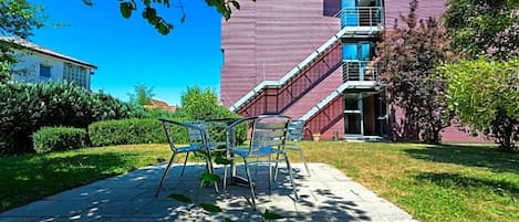 A building with a red exterior, a staircase, and a paved outdoor area with metal chairs.