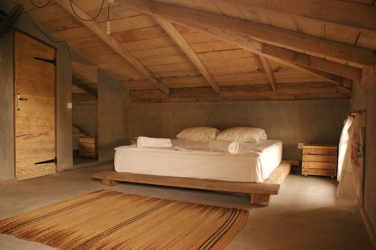 A wooden bedroom with a bed, a wooden bench, and a door.