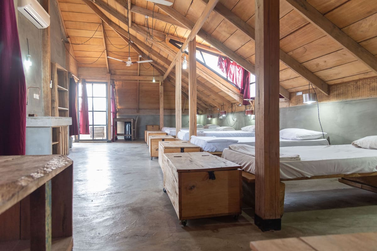 A rustic wooden cabin with multiple beds and a central seating area.