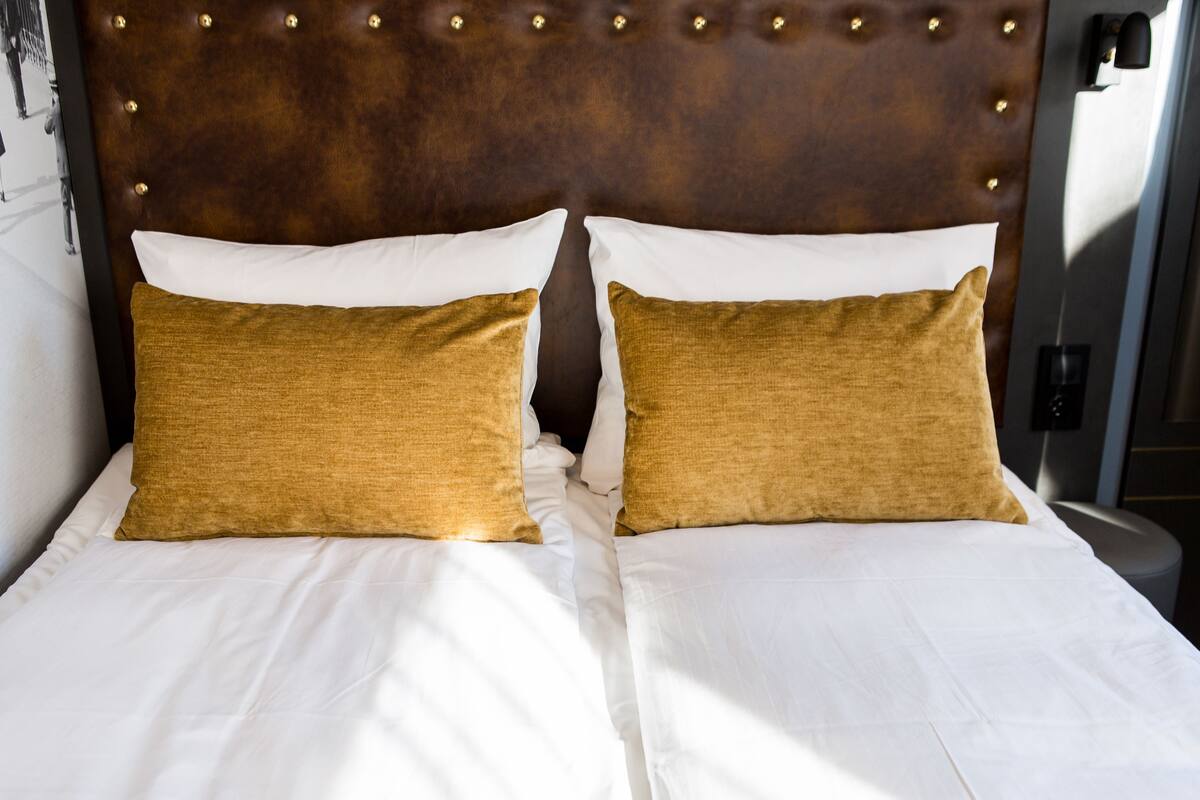 A bed with a tufted headboard, two pillows, and a white bedspread.