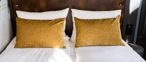 A bed with a tufted headboard, two pillows, and a white bedspread.