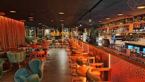 A bar area with rows of orange chairs and a bar counter with various bottles and glasses. - Hotel Verdandi Oslo (Oslo)