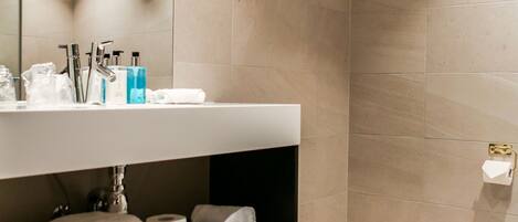 A modern bathroom with a large mirror, a sink, and a toilet.