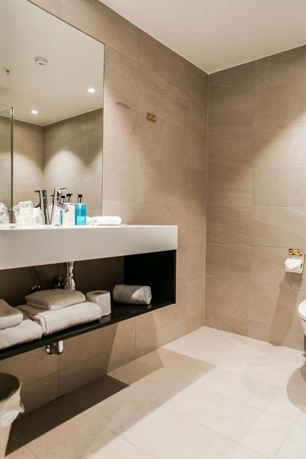 Un baño moderno con un espejo grande, un lavamanos y un inodoro.