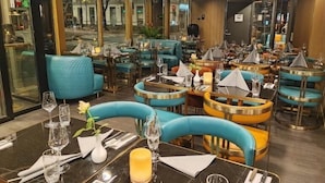 A restaurant interior with multiple tables and chairs, some with blue upholstery and others with gold accents. - Hotel Verdandi Oslo (Oslo)