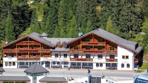 A hotel with a traditional Alpine architectural style, featuring wooden balconies and a central entrance. - Hotel Jú Furcia (Marebbe)