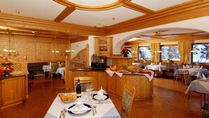 A spacious dining area with wooden furniture and a central island with a coffee machine. - Hotel Jú Furcia (Marebbe)