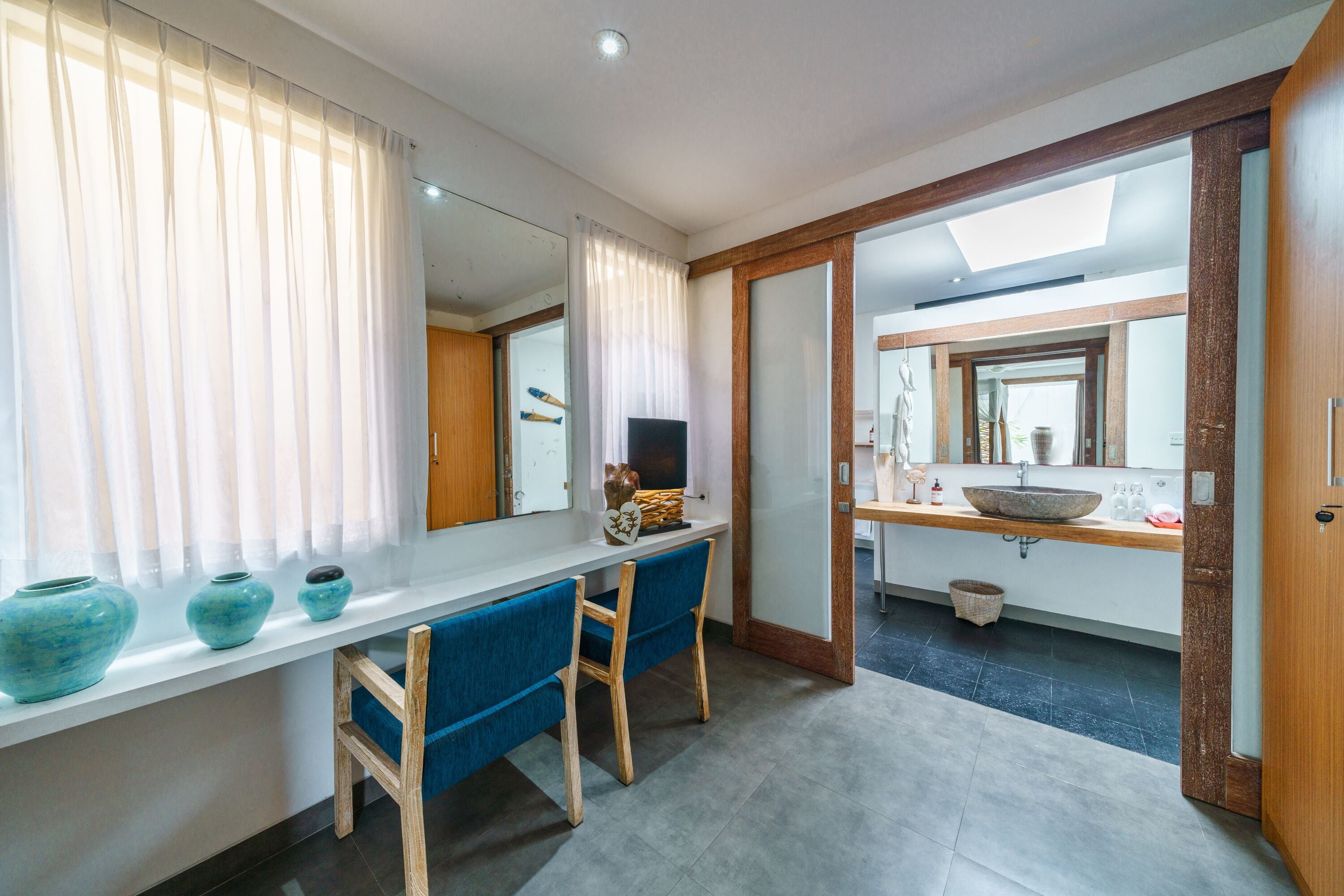 A modern bathroom with a large mirror, a sink, and a window with curtains.