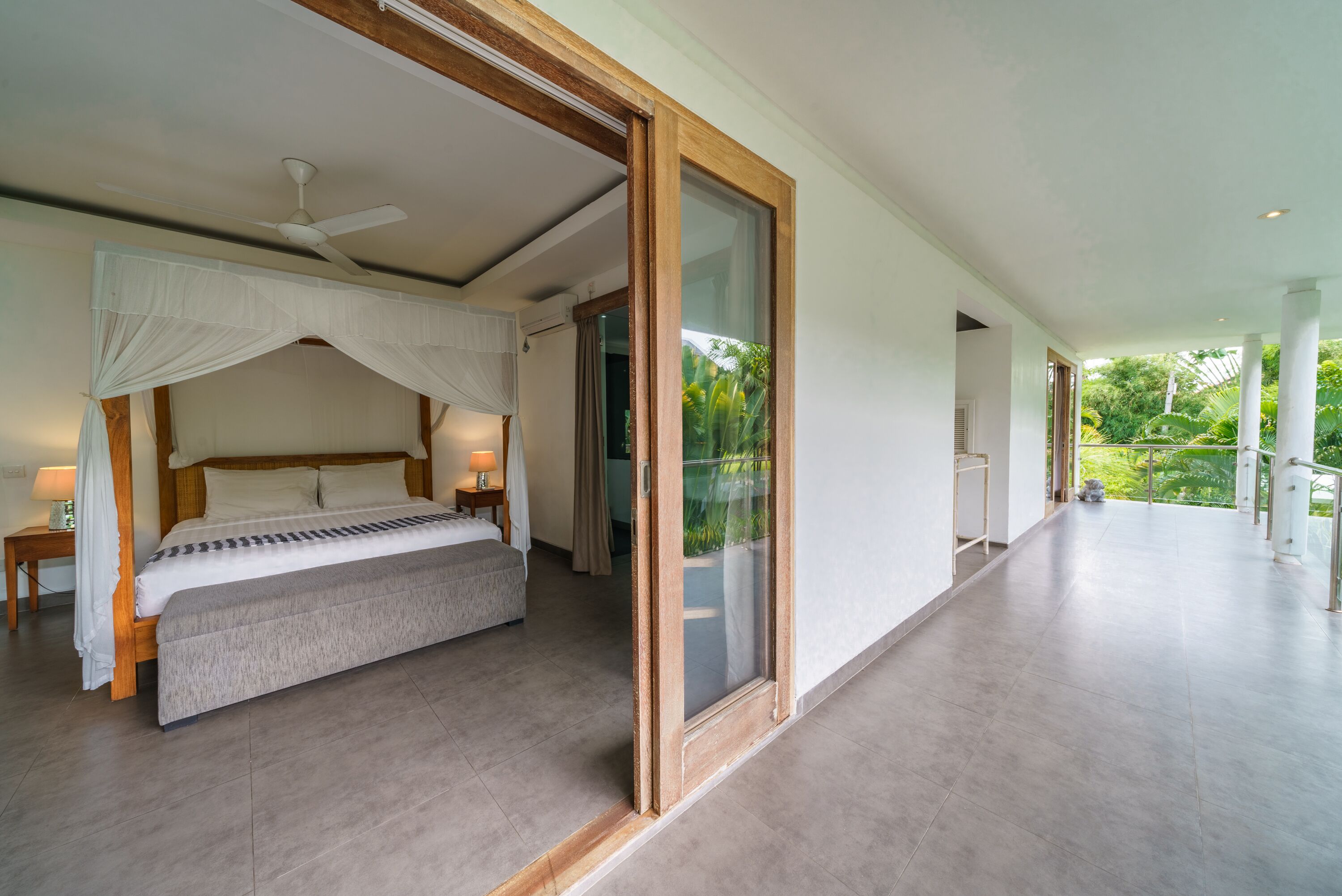 A spacious bedroom with a large bed, a ceiling fan, and a sliding glass door leading to a balcony.