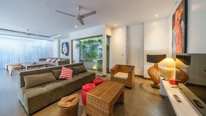 Una sala de estar moderna con un sofá, sillones, una mesa de centro y un mueble para televisión con una lámpara.