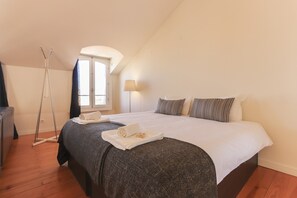 A bedroom with a bed, a standing lamp, and a window. - Santa Catarina Stylish by Homing (Lisbon)