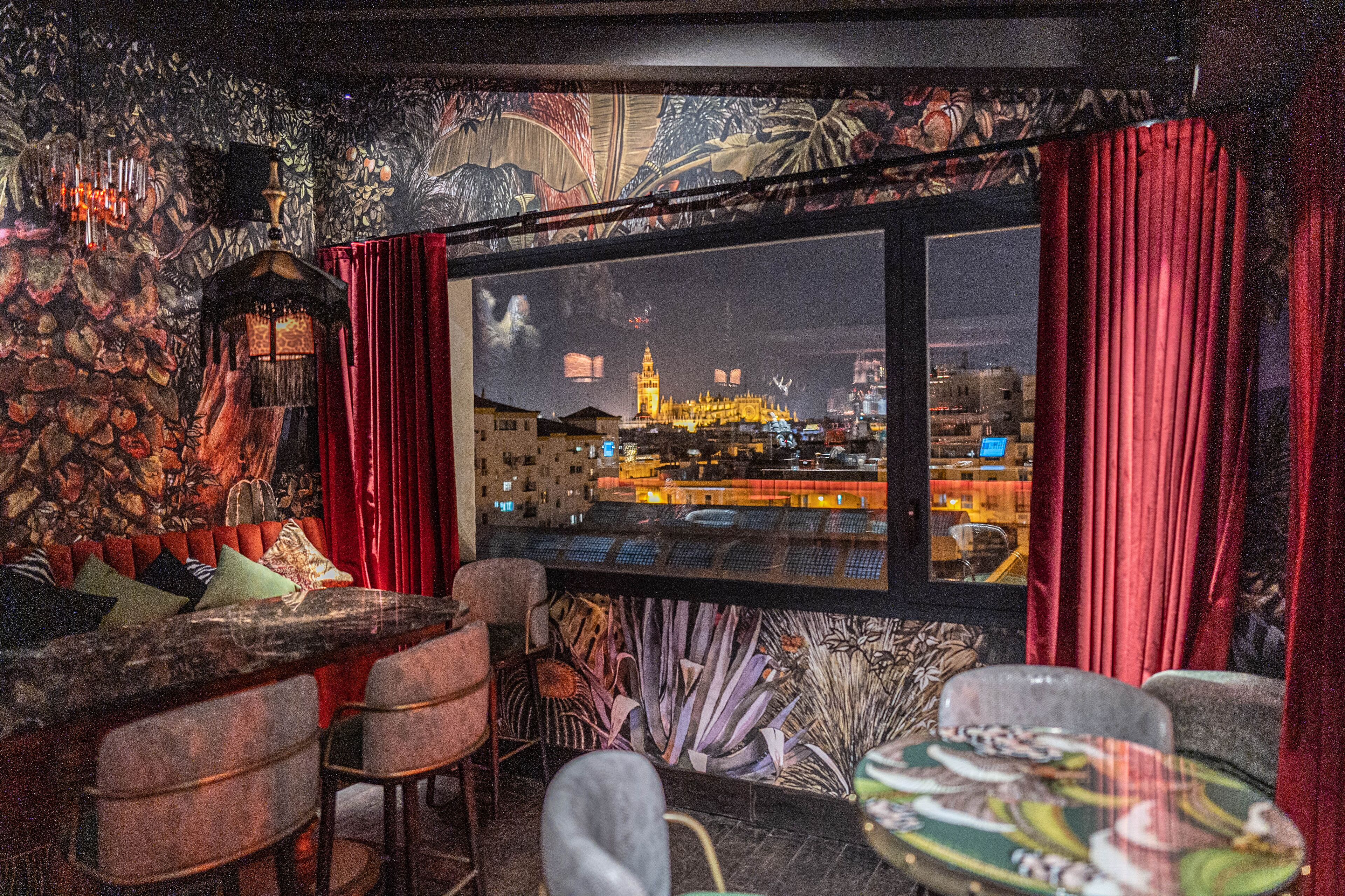 Un rincón de bar acogedor con vistas a la ciudad, asientos cómodos y una pared decorativa.