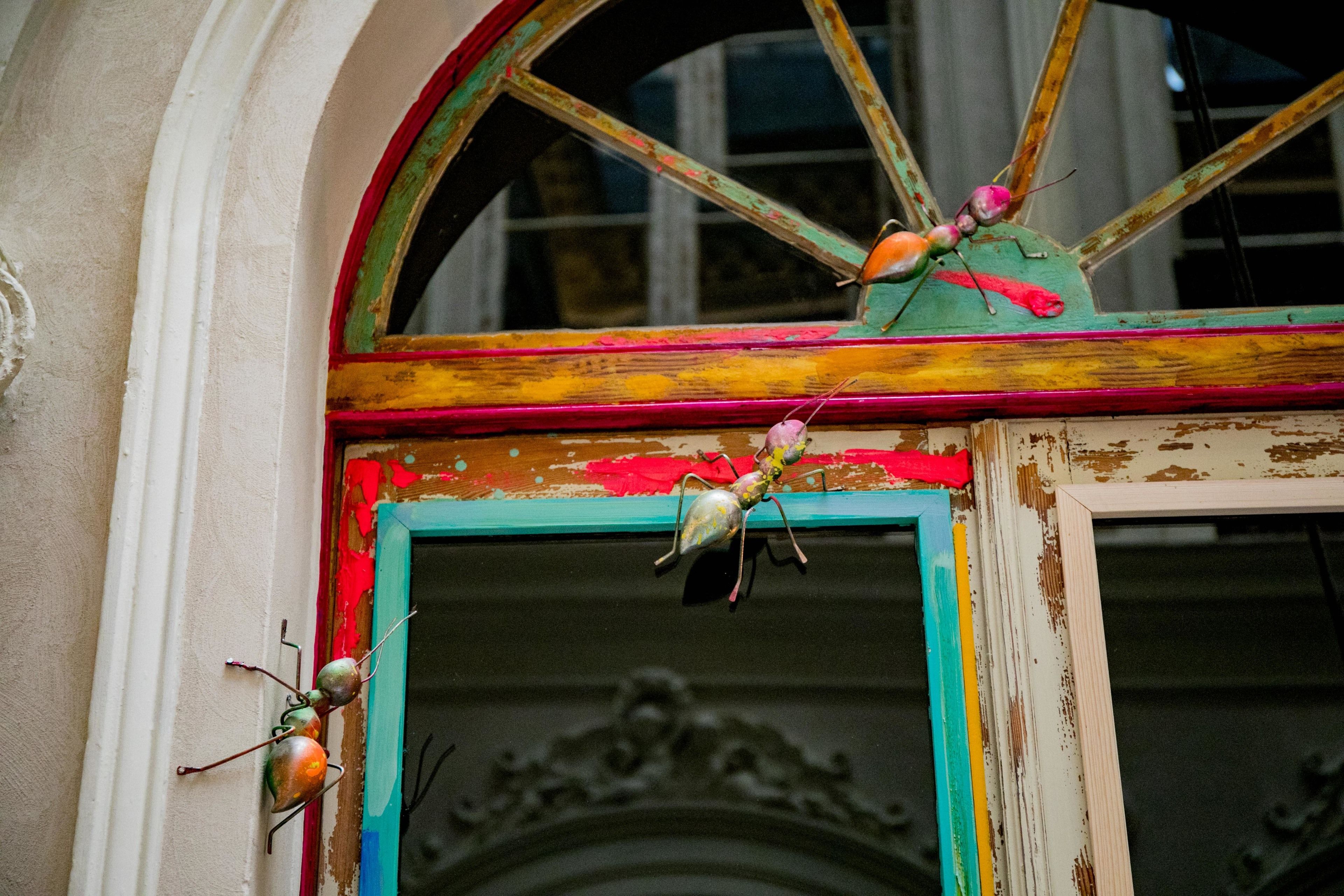 Una puerta rústica y colorida con un arco decorativo y una ventana encima.