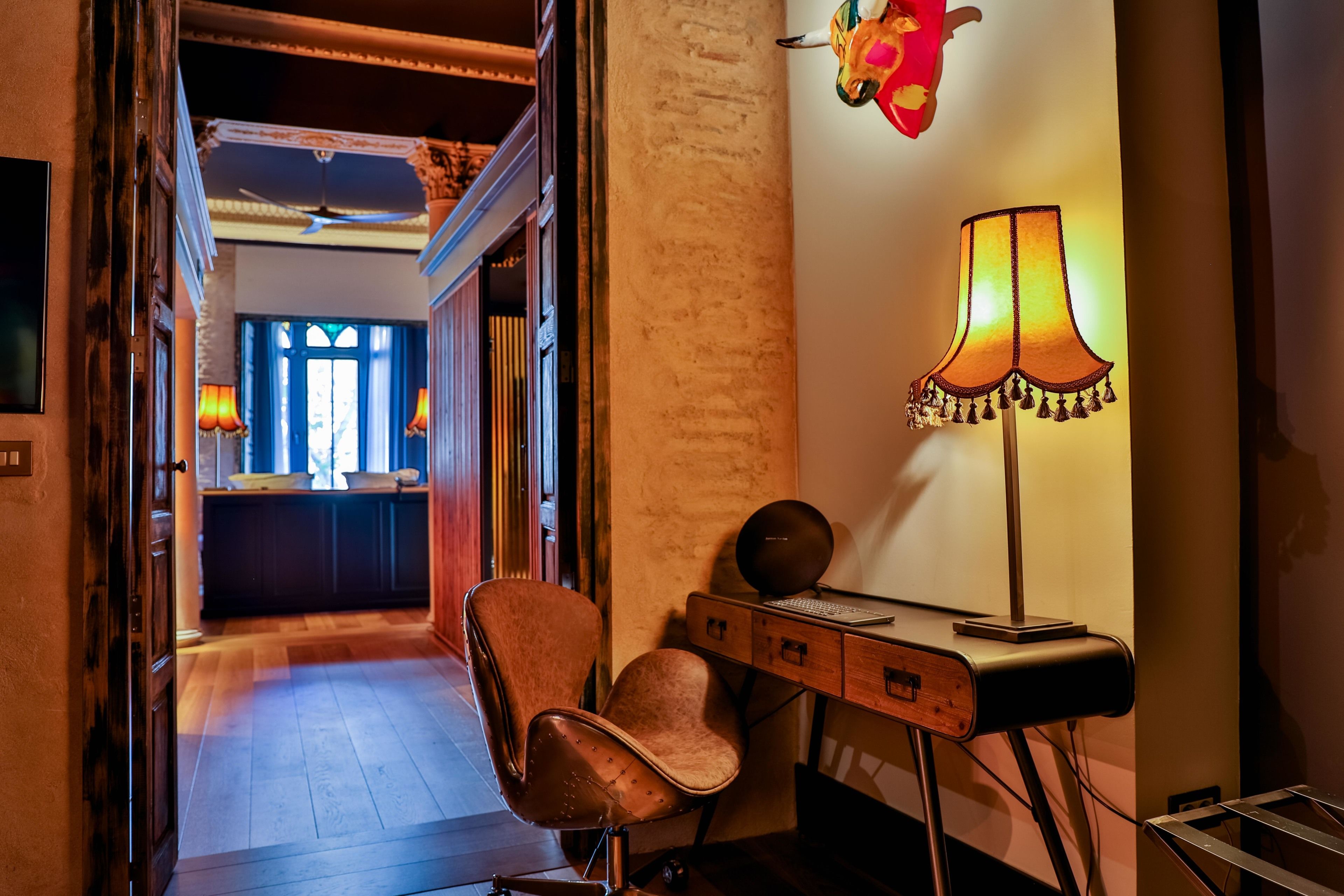 Une pièce comprenant un bureau en bois, une chaise, une lampe et un élément décoratif mural.