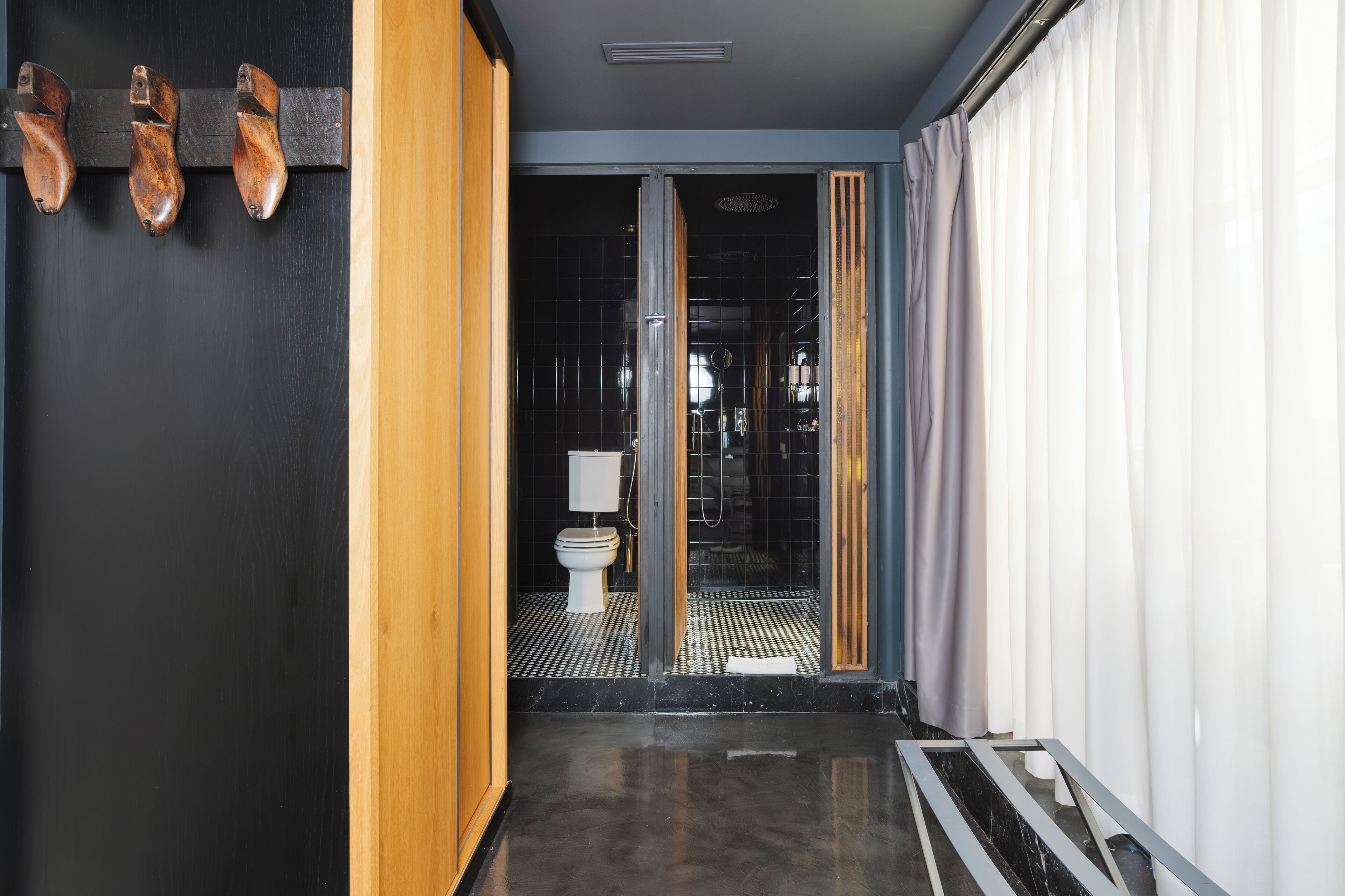 A modern bathroom with a black and white color scheme, a wooden door, and a glass shower enclosure.