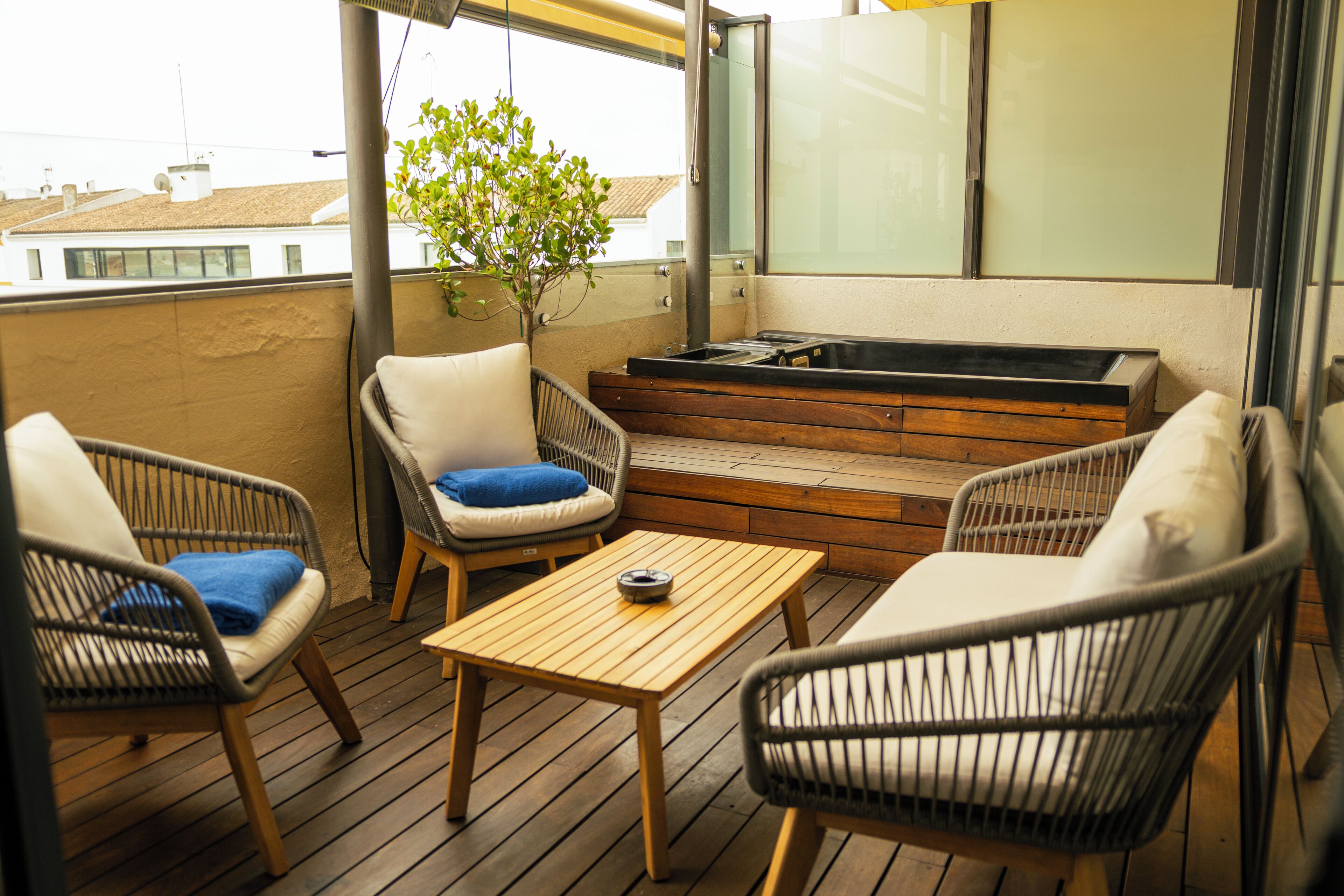 A balcony with wicker furniture, a wooden table, and a small plant.