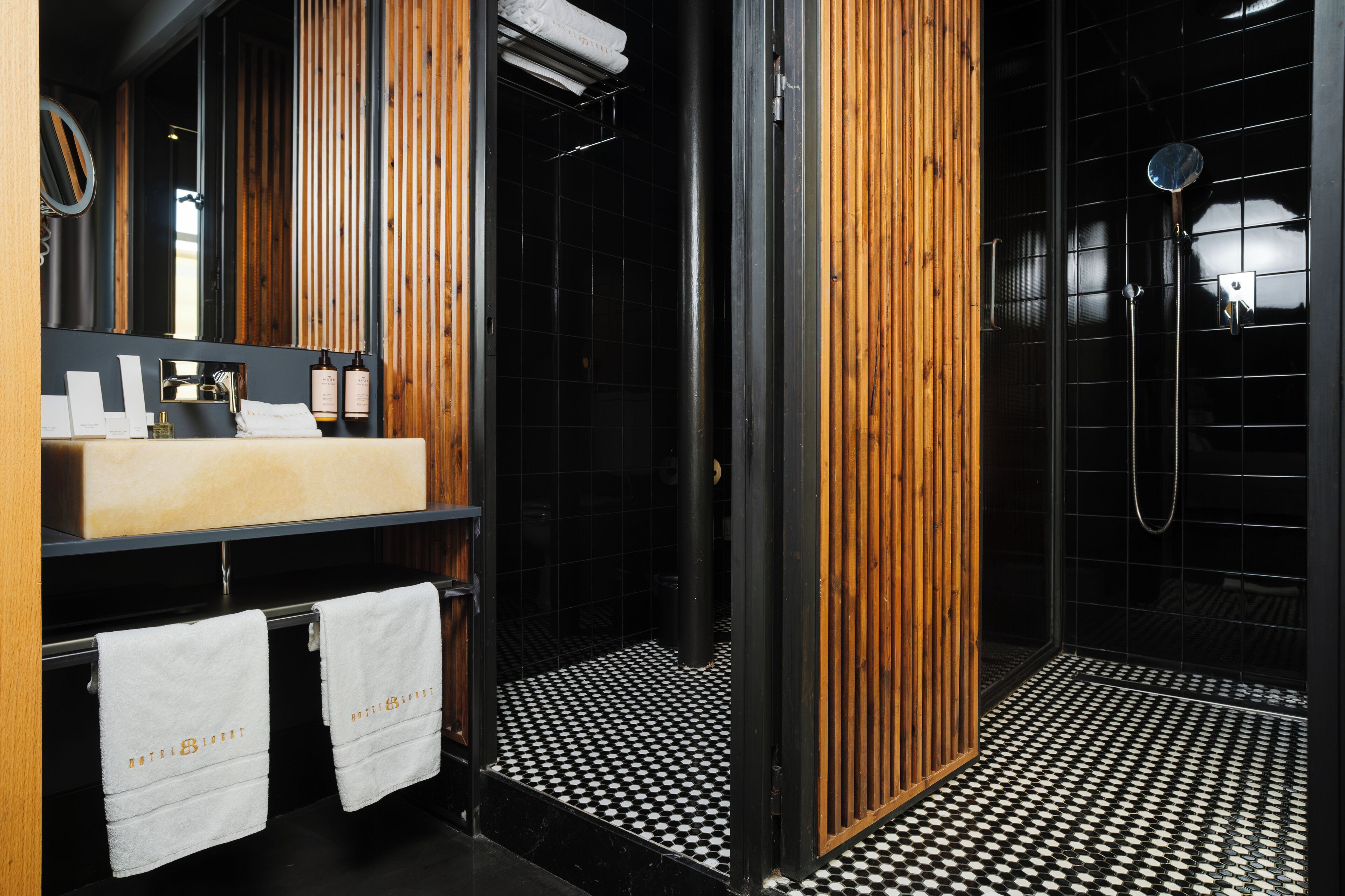 Ein modernes Badezimmer mit einem hölzernen Waschtisch, einem schwarz-weißen Schachbrettboden und einer Duschkabine aus Glas.