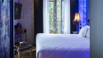 A modern hotel room with a large bed, a ceiling fan, a window with curtains, and a nightstand with a lamp.