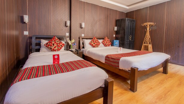 Two single beds with red and white bedding, wooden headboards, and a dark wooden wardrobe.