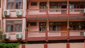 A multi-story building with balconies, air conditioning units, and a signboard.