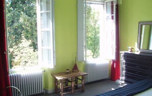 A room with a window, radiator, wooden table, dresser, and a mirror. - Chateau de Laric (Chabestan)