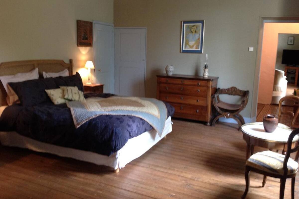 A bedroom with a bed, dresser, nightstand, and chairs.