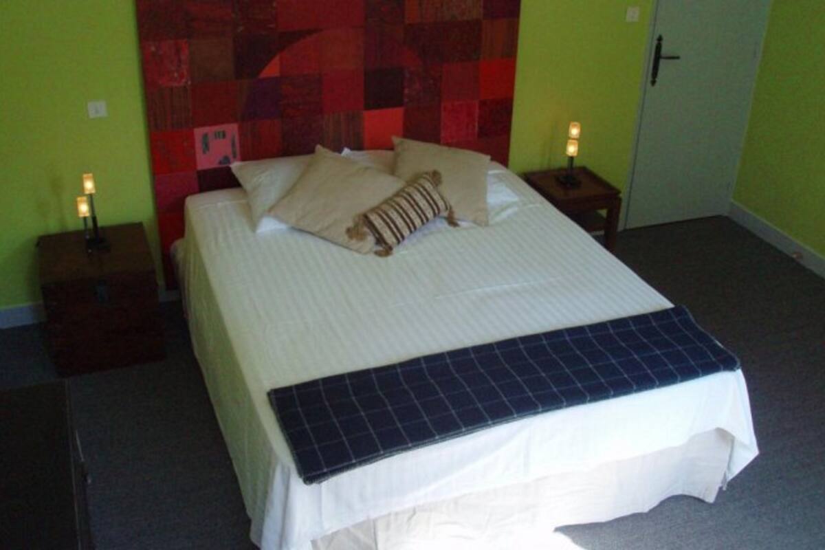 A bed with a quilted headboard, two bedside tables with lamps, and a door to the right.