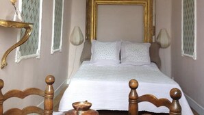 A bedroom with a bed, bedside lamps, a vase on a table, and a decorative wall piece. - Chateau de Laric (Chabestan)