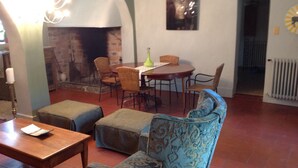A cozy living room with a fireplace, a dining table with chairs, and a patterned sofa. - Chateau de Laric (Chabestan)
