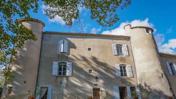 A building with a stone base, multiple windows with shutters, and a tiled roof. - Chateau de Laric (Chabestan)