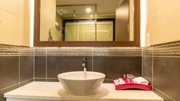 A bathroom with a large mirror, a vessel sink, and a wooden shelf.