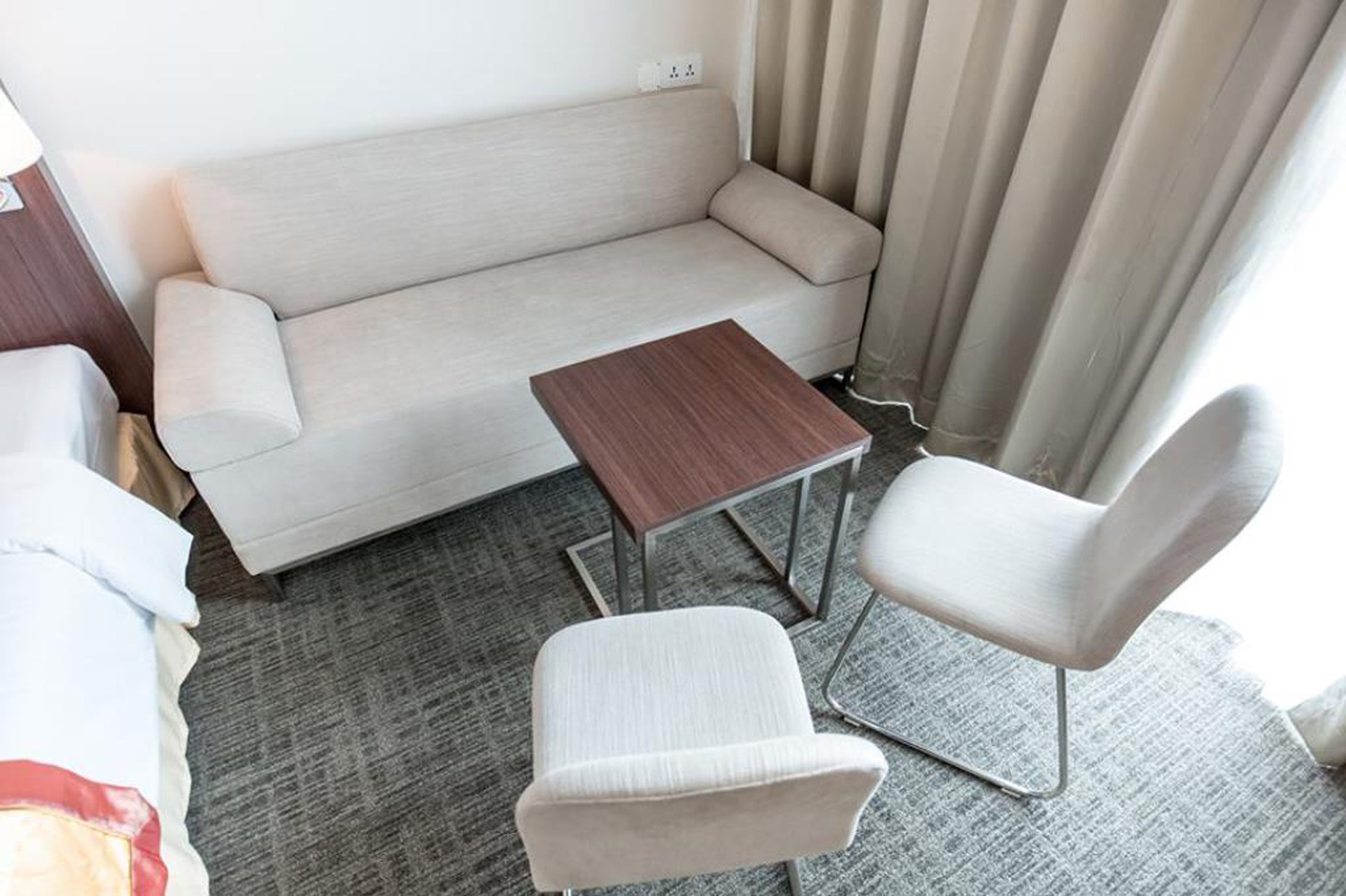 Una habitación de hotel moderna con un sofá, una mesita de madera y dos sillas.