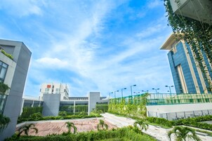 A modern building with a flat roof, large windows, and a landscaped area with pathways and greenery.