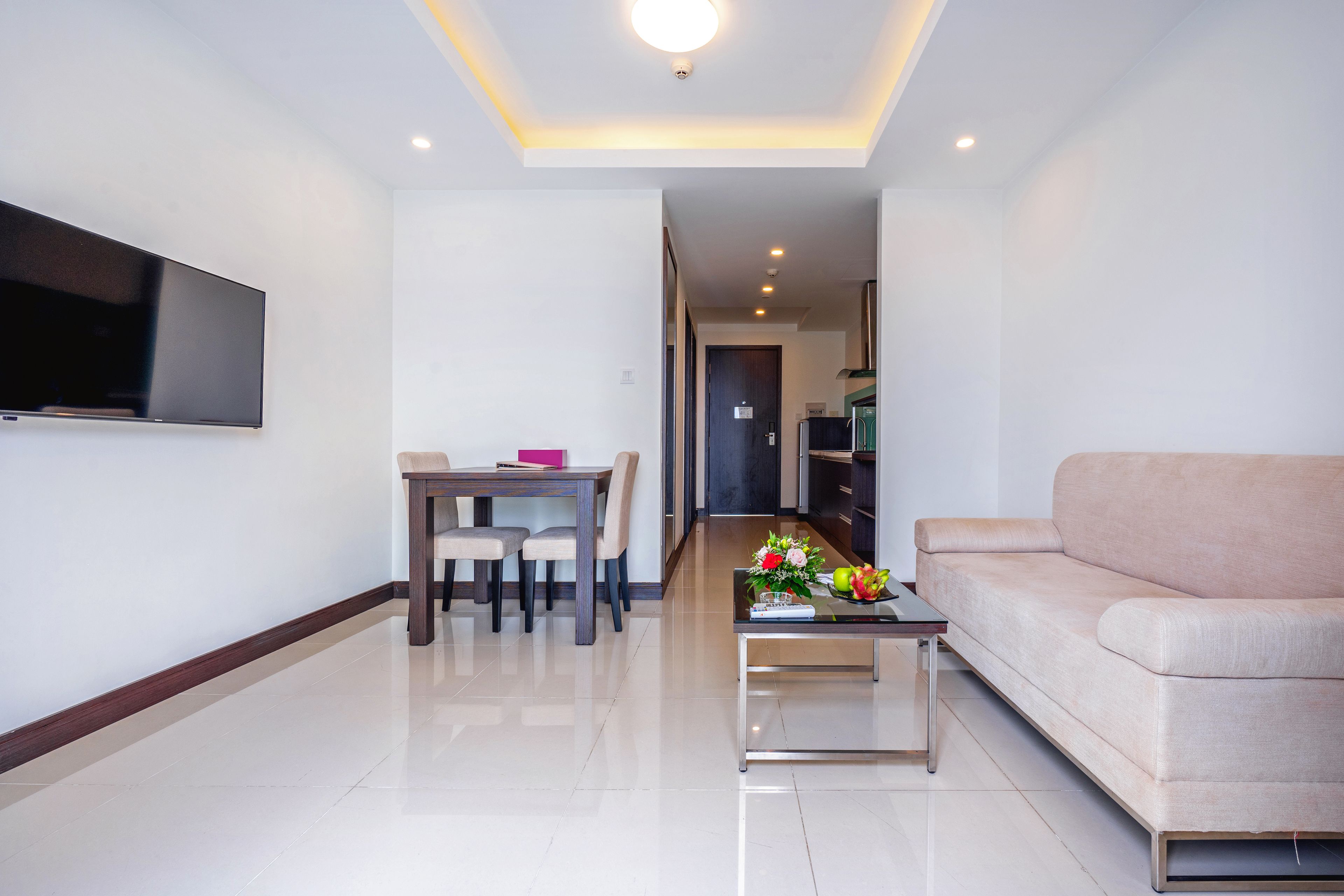 A modern living room with a flat-screen TV, a dining area with a table and chairs, and a sofa.