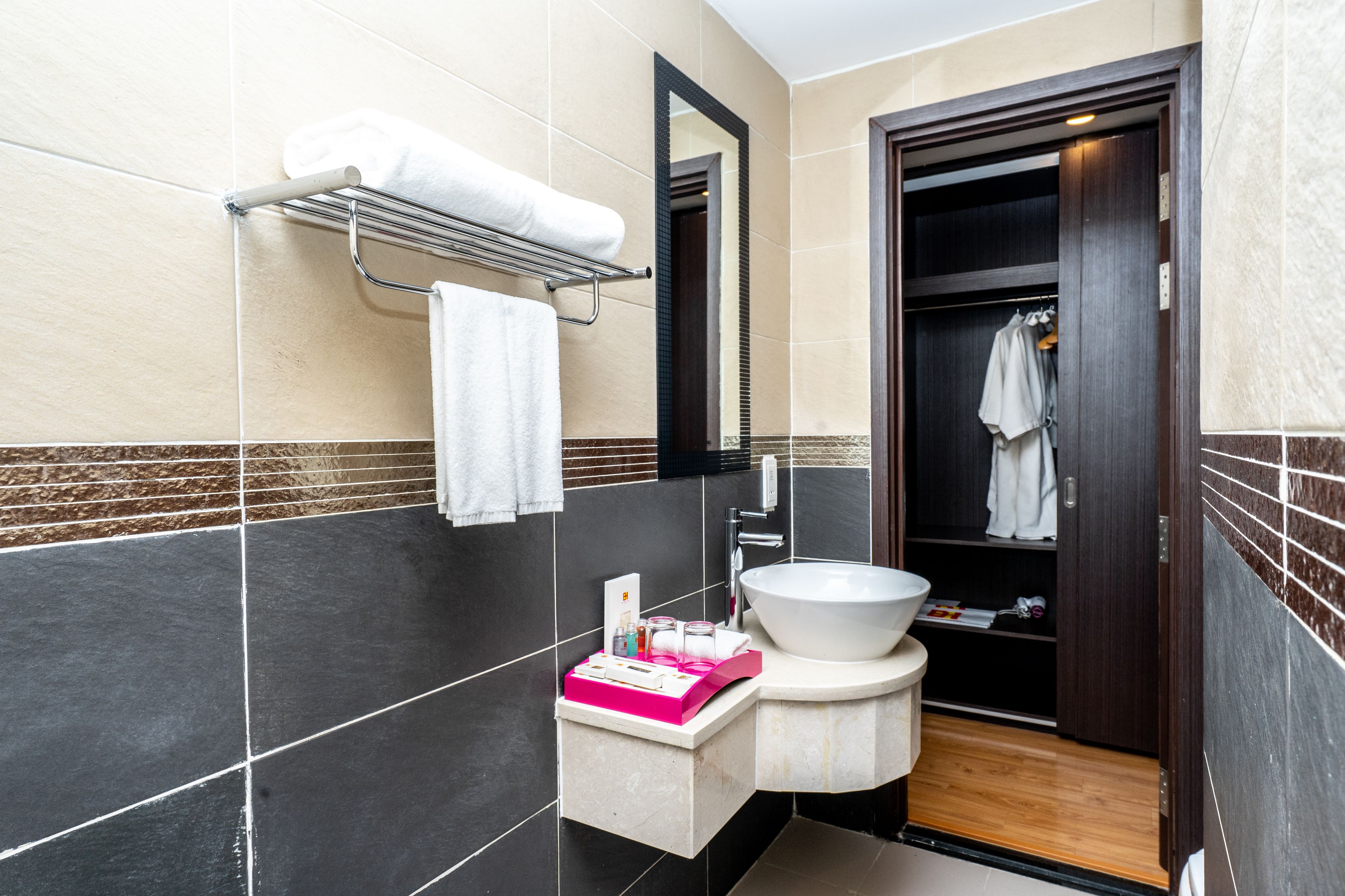 A modern bathroom with a large sink, a towel rack, and a mirror.