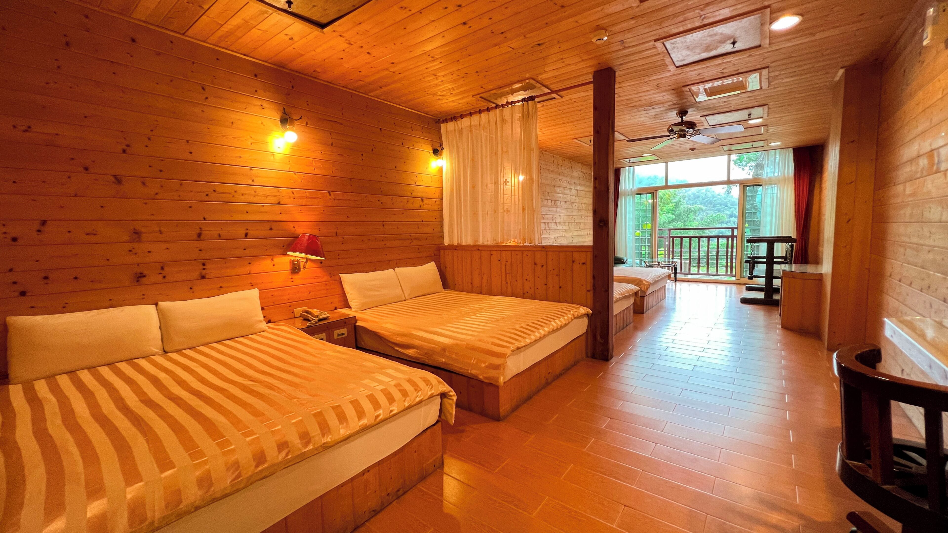 A wooden cabin with two beds, a balcony, and a wooden floor.