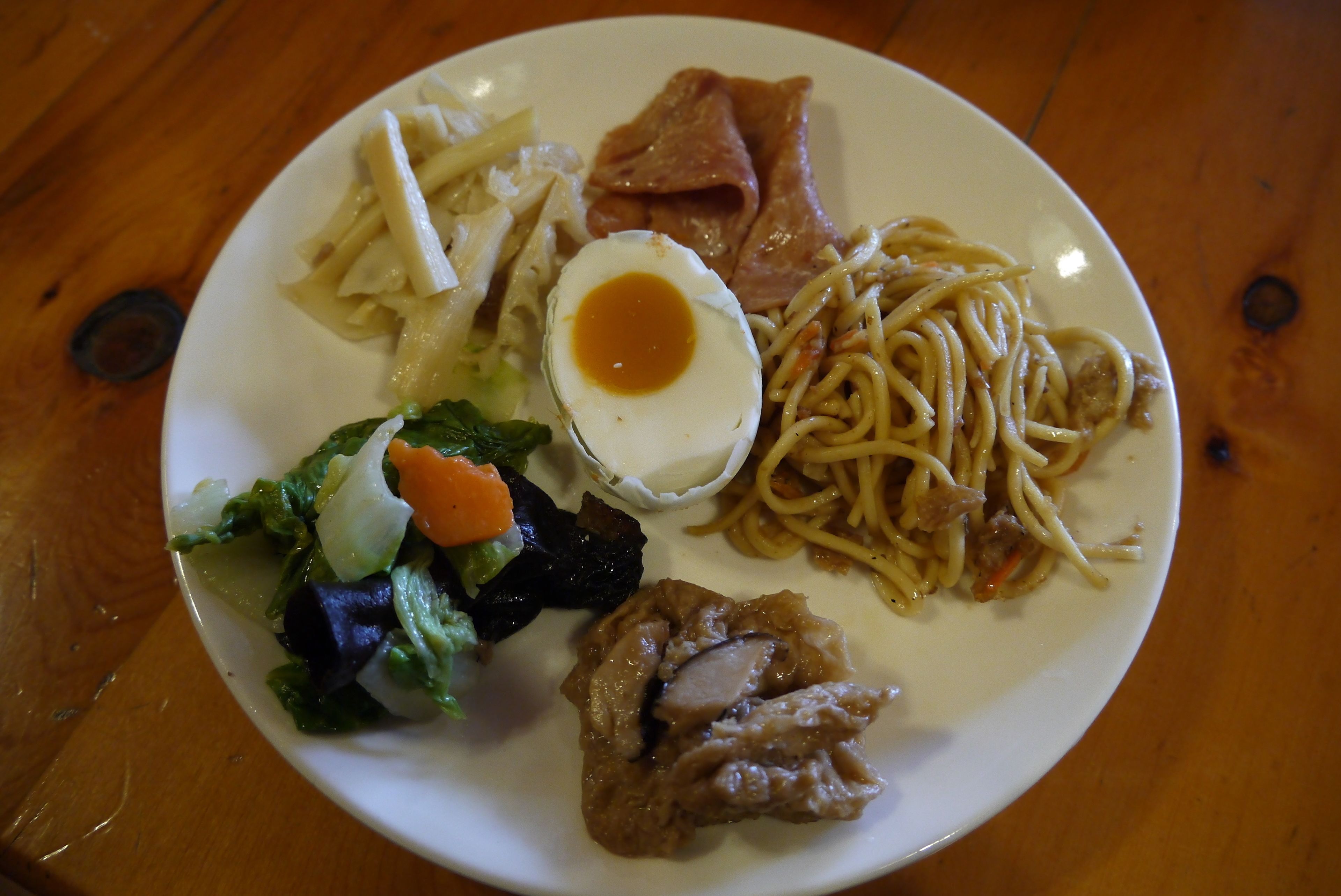 A plate with various food items including noodles, a boiled egg, and vegetables.