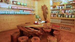 A wooden interior with a central table surrounded by stools, shelves with packaged goods, and a large wooden sculpture. - King Taiwan (Lugu)