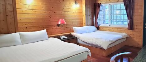 Una camera da letto in una casetta di legno, con due letti, un comodino, una lampada e una finestra con tende.