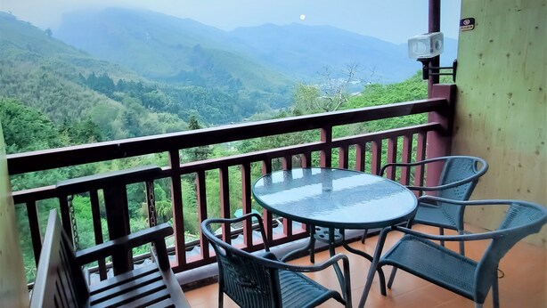 A balcony with a glass table and four chairs, overlooking a mountainous landscape. - King Taiwan (Lugu)