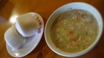 Un tazón de sopa con vegetales y un plato con dos albóndigas.